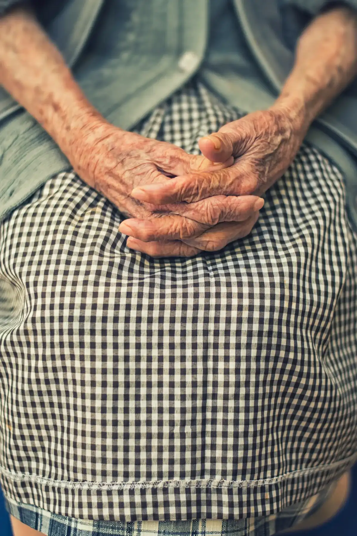 Les mains d’une personne âgée posées sur ses genoux